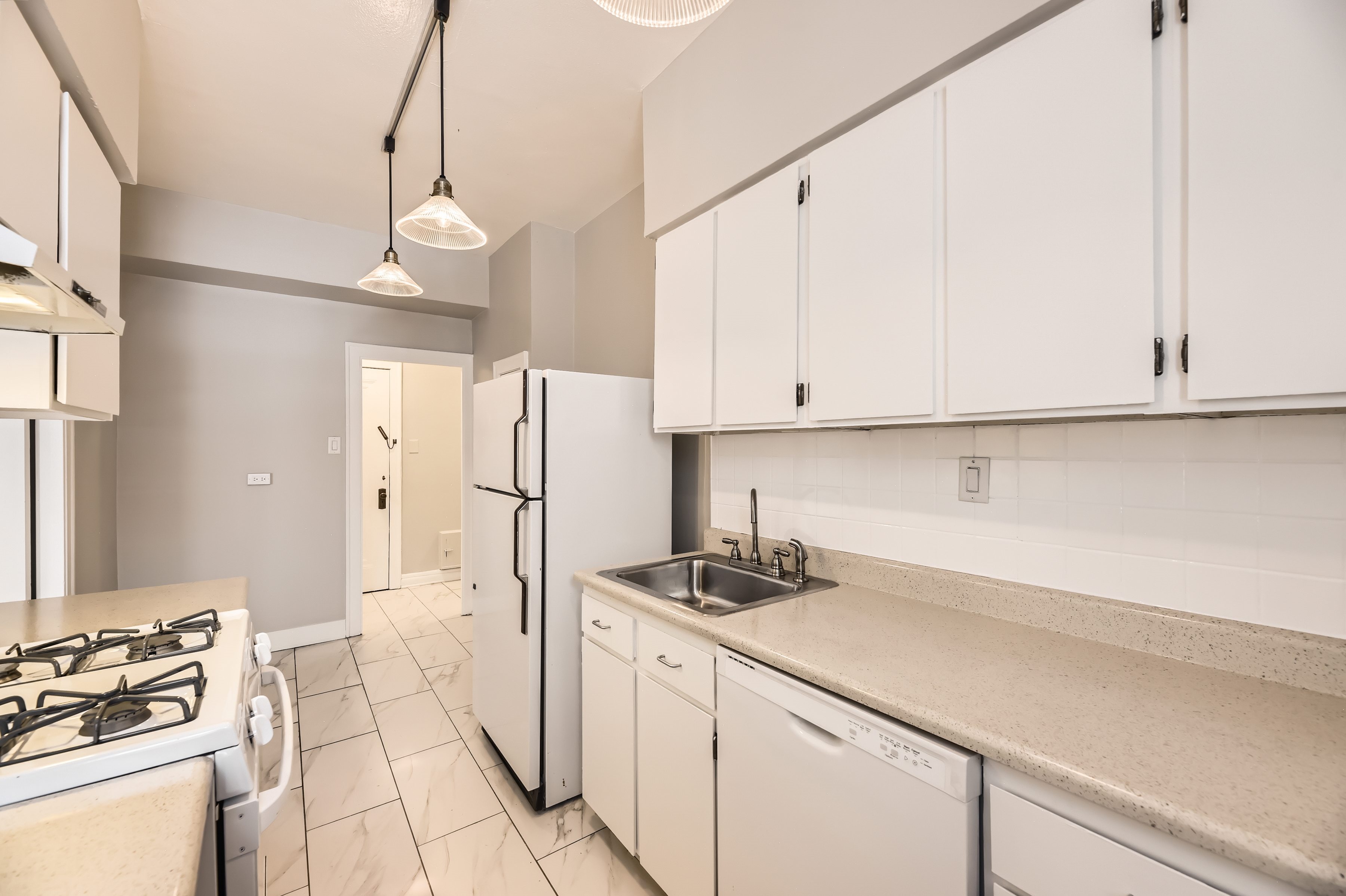A kitchen with white cabinets and a white refrigerator.